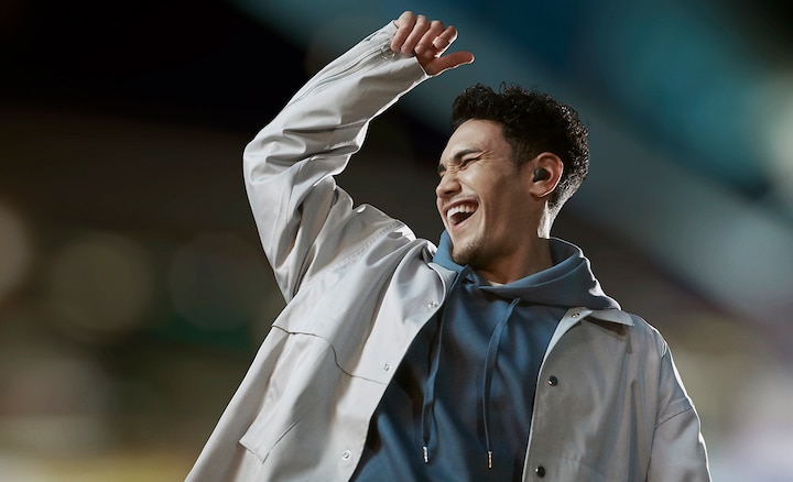 Split screen image of a man dancing in a blurred stadium environment wearing LinkBuds S with Noise Cancelling on and arm raised