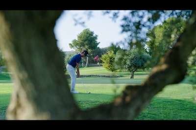 Example image of a golf player in focus with a tree trunk defocused in the foreground