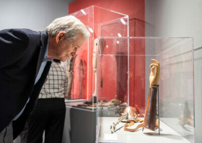 Exhibition attendee viewing prosthetic arm artifact from the Bespoke Bodies exhibition.