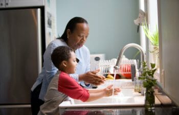 Woman and young boy washing their hands together