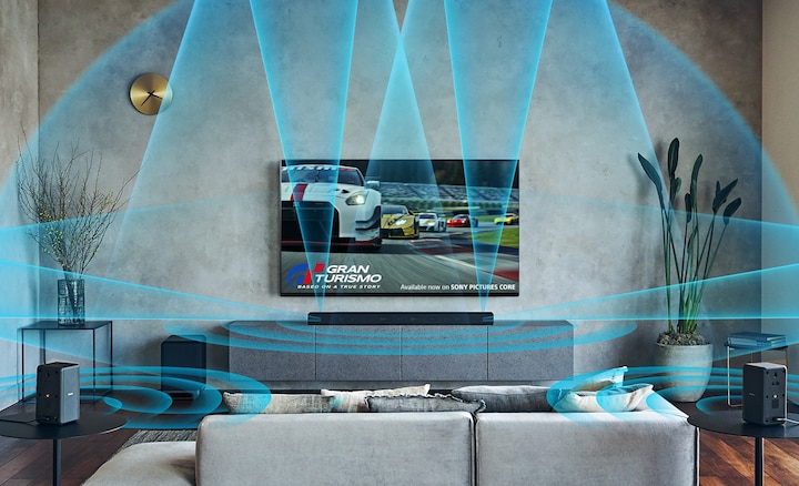 A living room with a wall-mounted BRAVIA TV, with illustrated blue sound waves representing surround sound