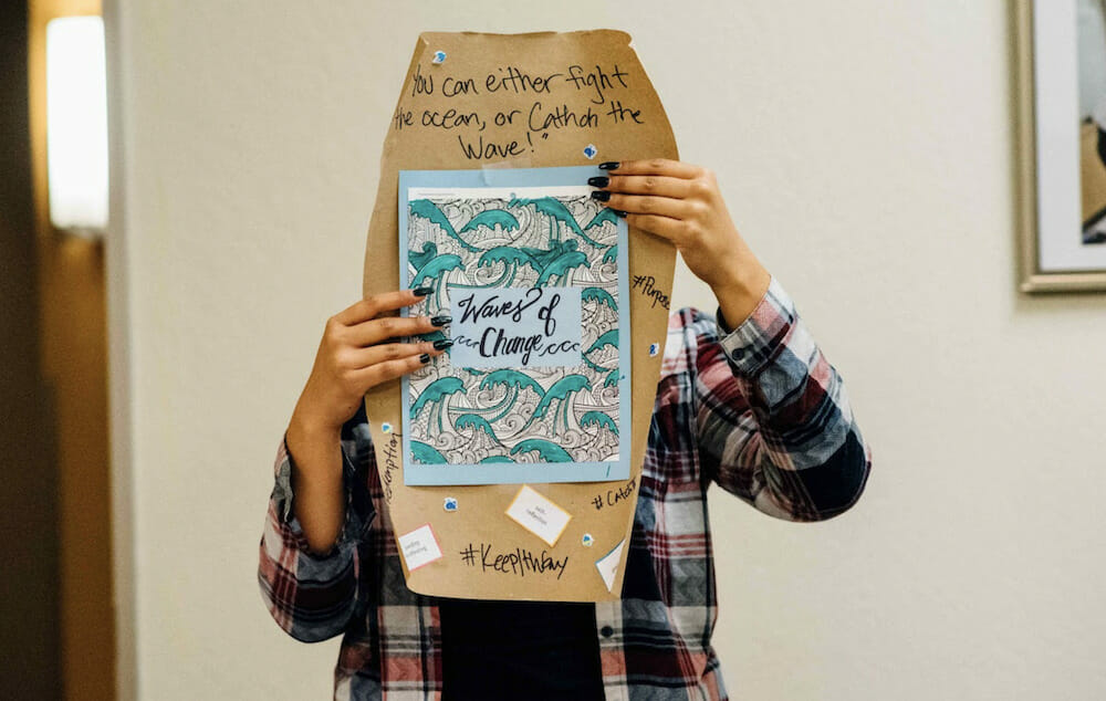 Person holding up brown and blue decorated sign