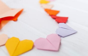 Yellow, pink, purple, and red paper hearts connected by a string