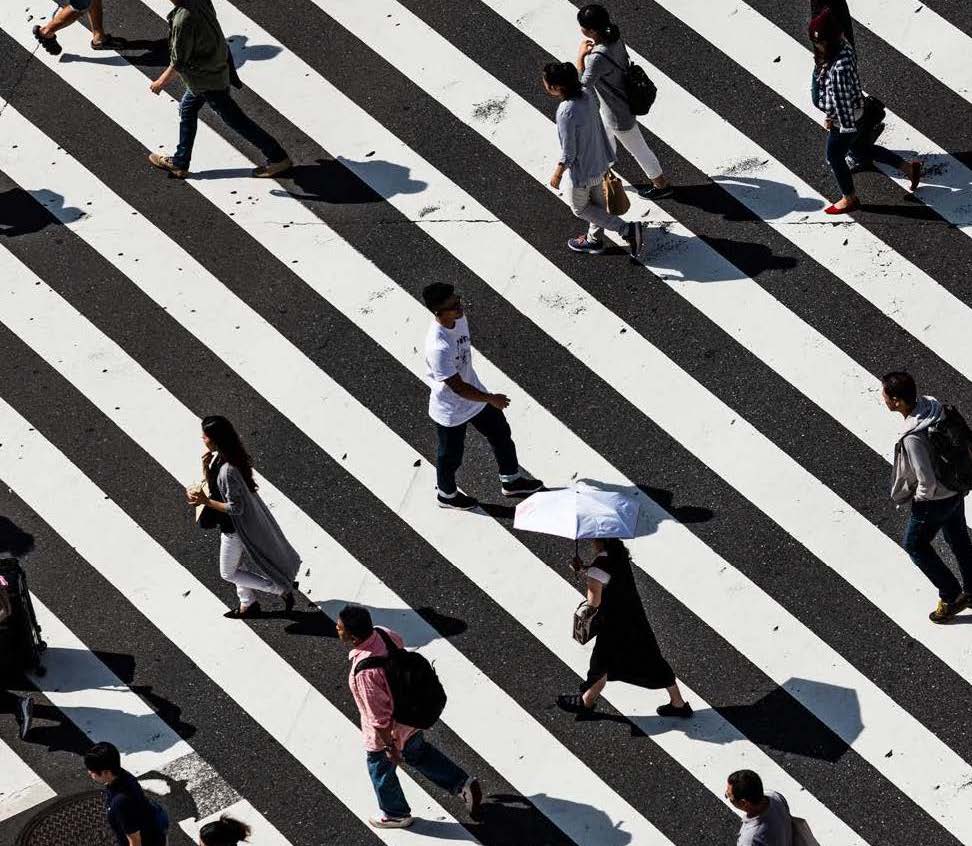 Crowd of people walking against black and white striped background.