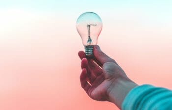 Person holding lightbulb against a sunset