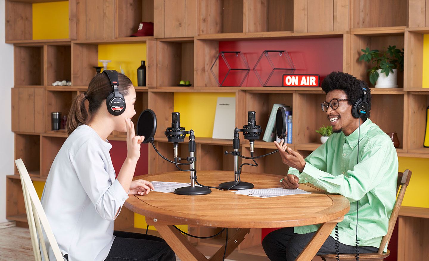  Image of a man and a woman sitting at a table in a studio recording with Sony C-80 microphones.