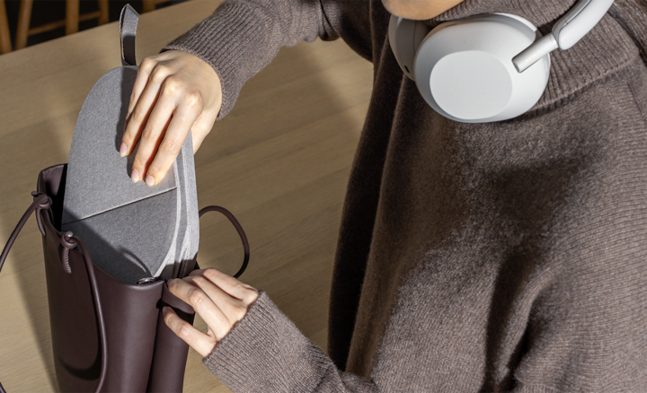 Woman wearing headphones slipping carrying case into handbag