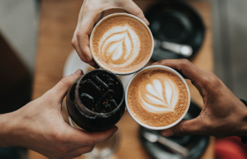 Photo of a group of people having coffee. Overhead view of coffee cups with coffee art.